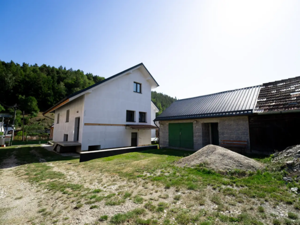Dvor medzi rodinným domom a hospodárskou budovou s garážou.