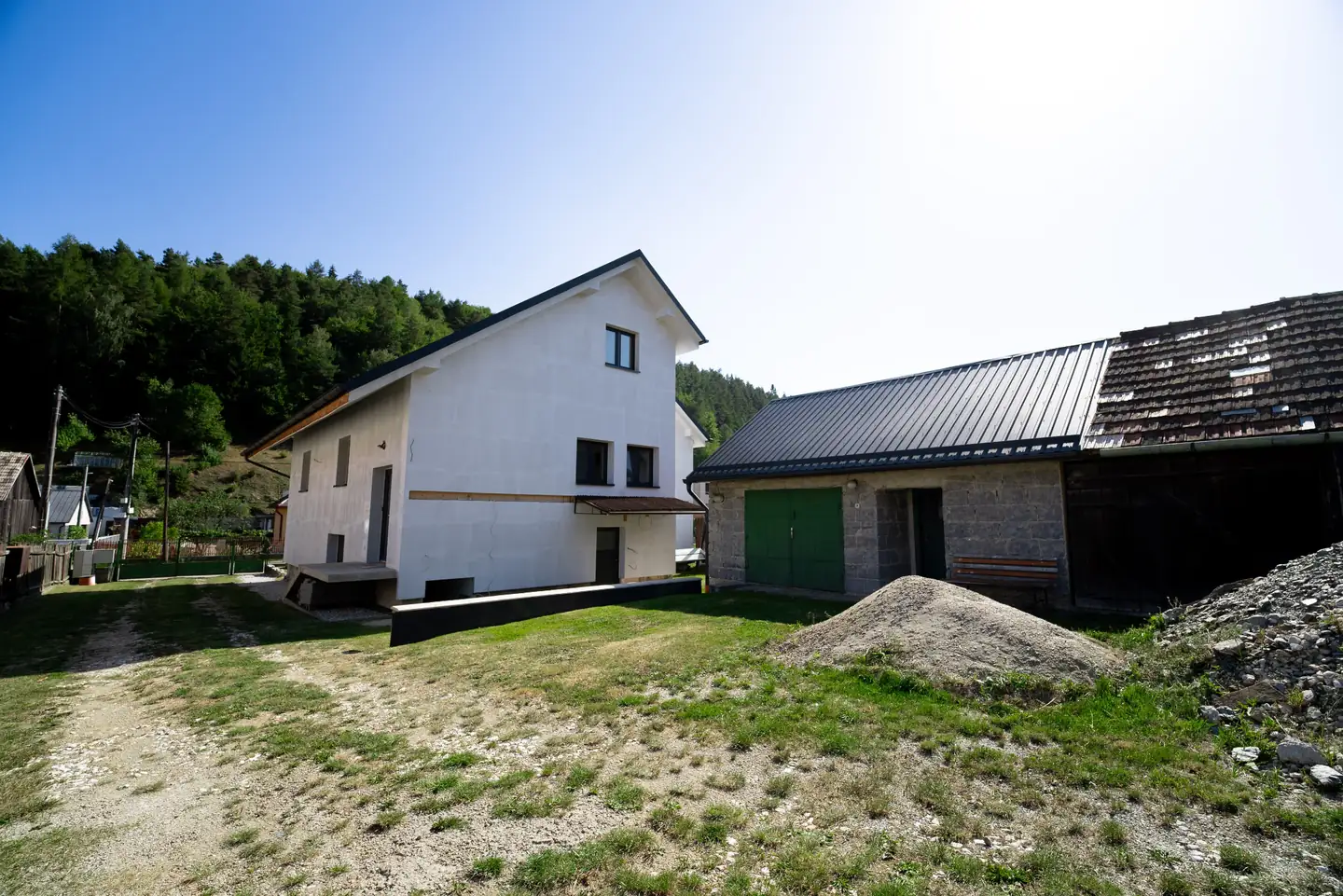 Dvor medzi rodinným domom a hospodárskou budovou s garážou.